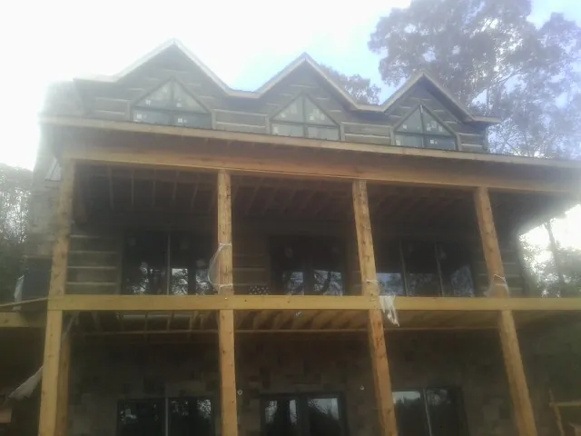 Dormers and porch framing on a large log home under construction — Roof Coating work by our crew in Franklinton